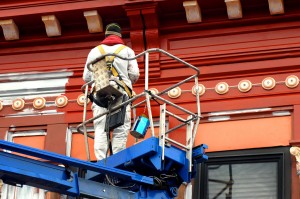 painter-painting-commercial-building-exterior-standing-in-platform-lift