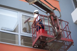 worker-cleaning-high-windows-in-office-building-from-cherry-picker
