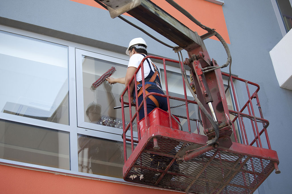 worker-cleaning-high-windows-in-commercial-building-from-cherry-picker