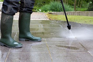 worker-in-wellington-boots-power-washing-patio-with-high-pressure-water