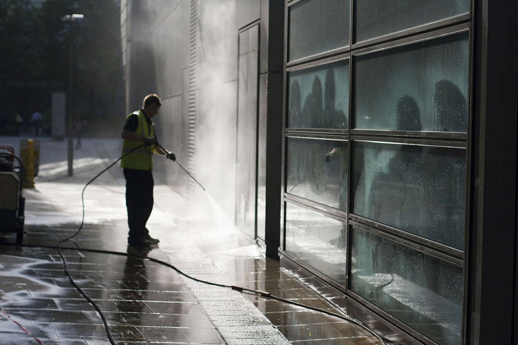 worker-power-washing-exterior-of-commercial-building-from-the-street